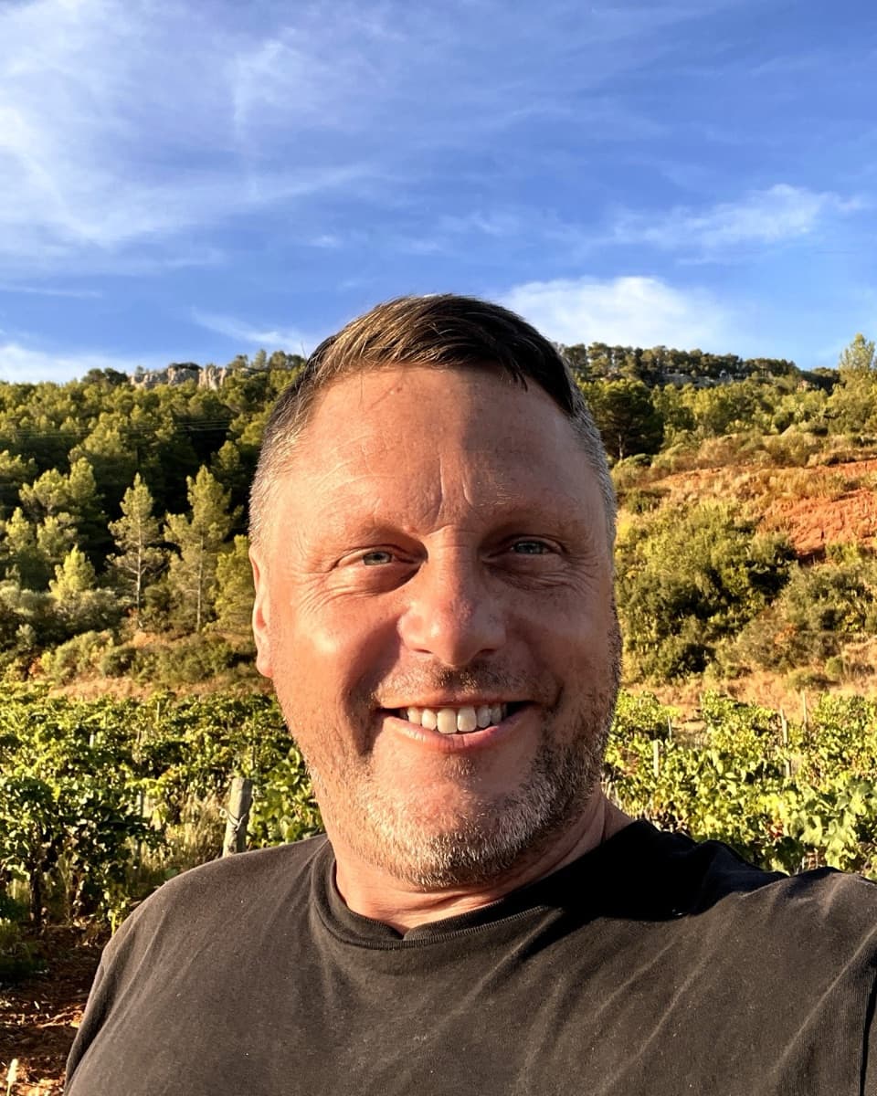 Shane Price, founder of AssetOS, outdoors in a vineyard